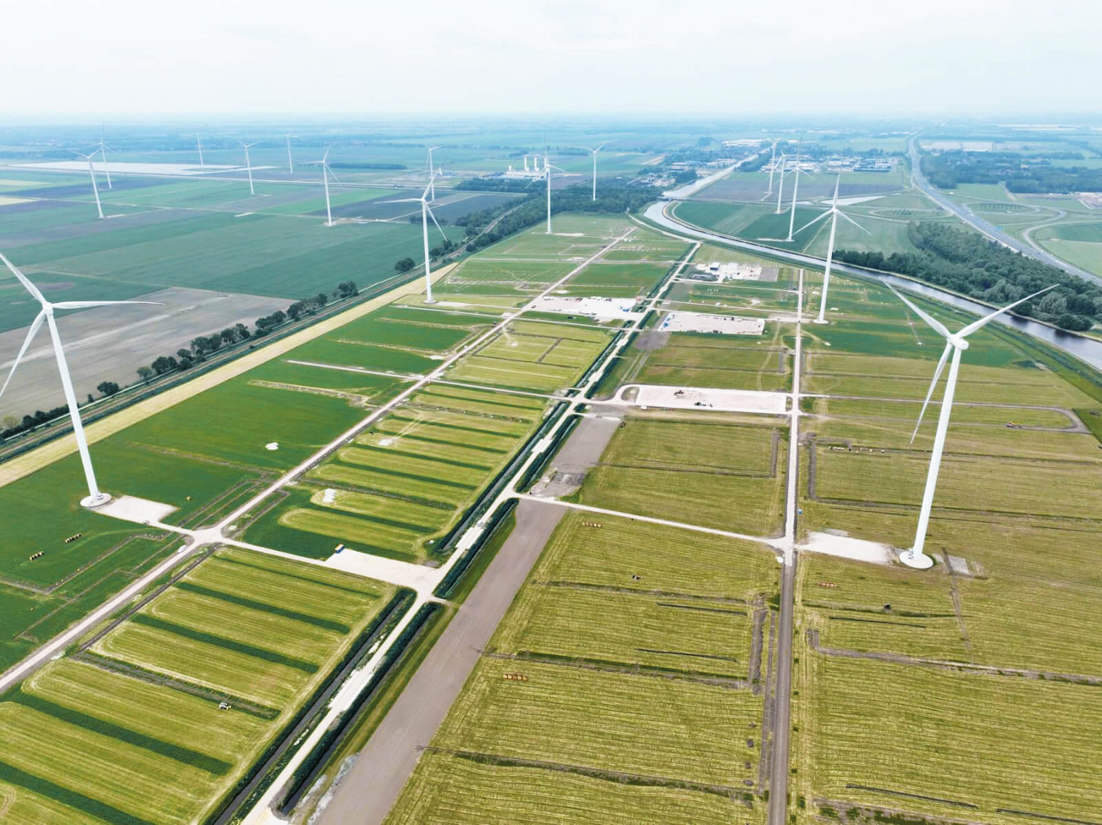 construction site of a solar farm with wind turbines in the background seen from above
