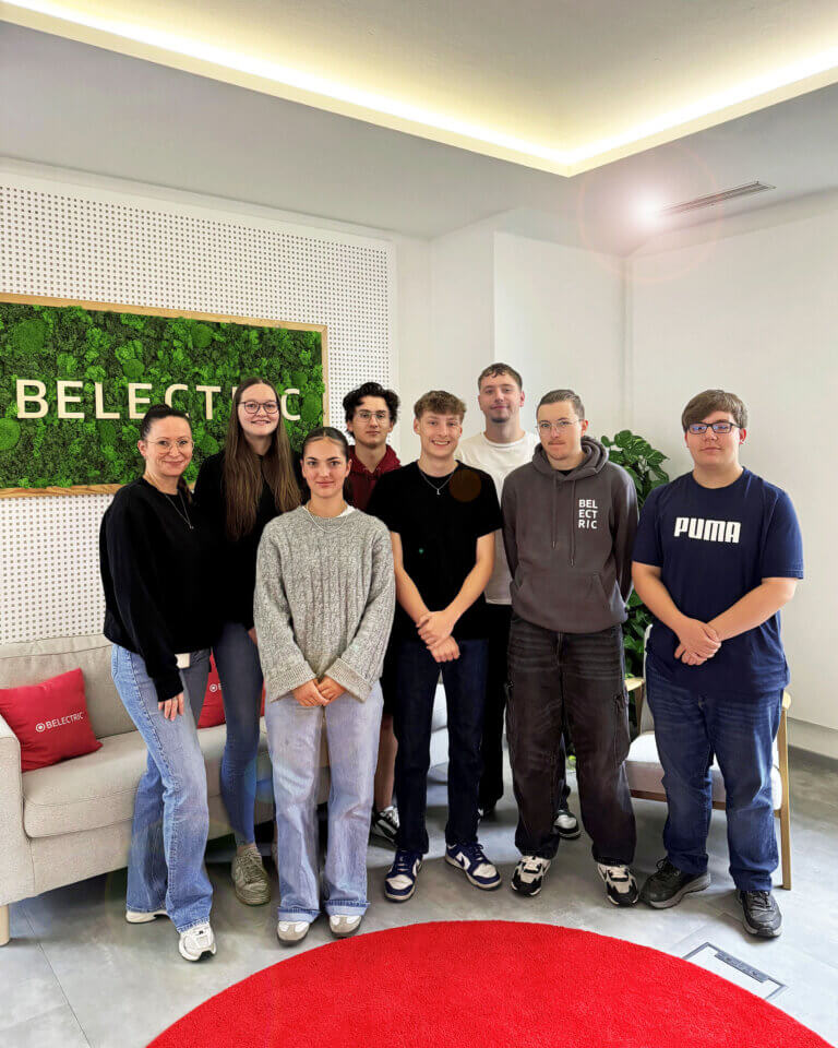 BELECTRIC's new trainees and their training officer stand in the company's canteen. In the group photo, everyone smiles into the camera.