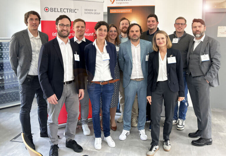 At BELECTRIC, a cluster meeting on battery storage took place. In the picture, some of the participants stand together for a group photo, similing into the camera.